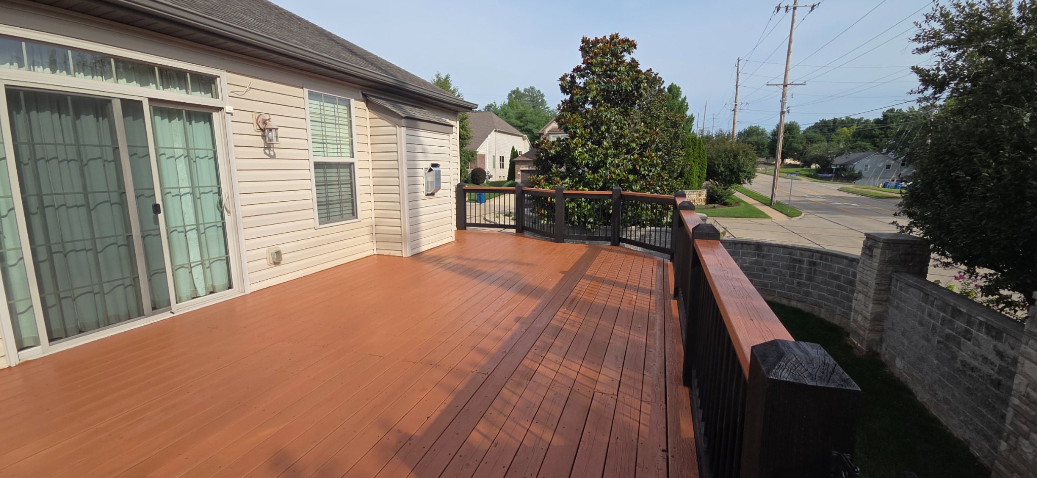 Freshly finished deck boards with black railings and matching reddish-brown top rails