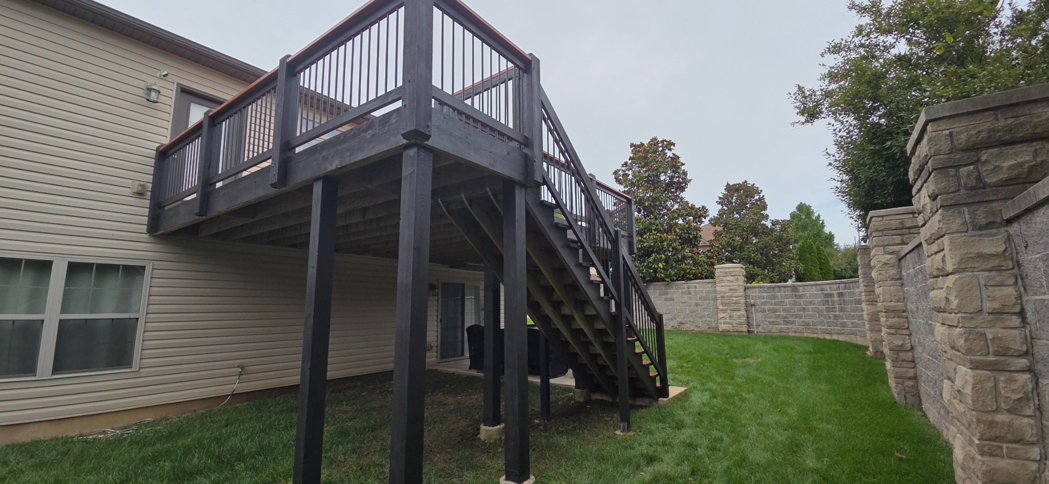 Side view of the finished elevated deck, support posts, railings, and exterior staircase